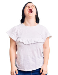 Brunette woman with down syndrome wearing casual white tshirt angry and mad screaming frustrated and furious, shouting with anger. rage and aggressive concept.