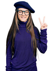 Young brunette girl with long hair wearing french look with beret and glasses smiling with happy...