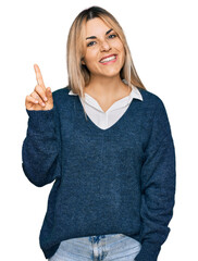 Young caucasian woman wearing casual clothes pointing finger up with successful idea. exited and happy. number one.
