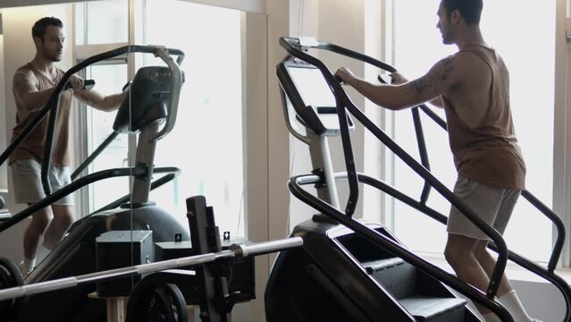 Silhouetted Man Walking up on Stepmill Machine at Indoor Gym To Burn Calories. Adult Male With Beared Doing Cardio at MOdern Health Club