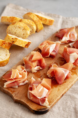 Slices of Appetizing Jamon Serrano Ready to Eat on a rustic wooden board, side view.