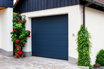 automatic garage doors near manicured blooming roses - obrazy, fototapety, plakaty