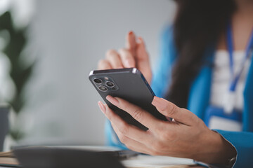 Beautiful asian woman looking at data on phone, businesswoman working in office attentively to grow and modernize start-up business, she is analyzing company's market and financial data.