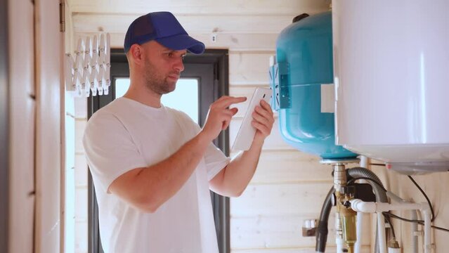 The technician checking the heating system in the boiler room with tablet in hand. 