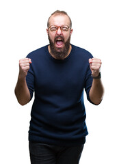 Fototapeta premium Young caucasian hipster man wearing sunglasses over isolated background excited for success with arms raised celebrating victory smiling. Winner concept.