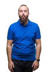 Young caucasian hipster man wearing blue shirt over isolated background making fish face with lips, crazy and comical gesture. Funny expression.