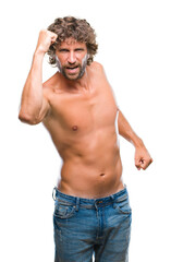Fototapeta premium Handsome hispanic model man sexy and shirtless over isolated background angry and mad raising fist frustrated and furious while shouting with anger. Rage and aggressive concept.