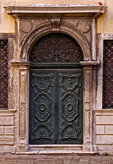 A wooden green decorated door  in the old Ghetto of Venice