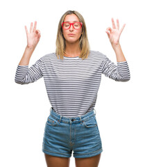 Fototapeta na wymiar Young beautiful woman wearing glasses over isolated background relax and smiling with eyes closed doing meditation gesture with fingers. Yoga concept.