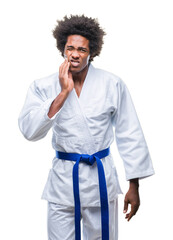 Afro american man wearing karate kimono over isolated background touching mouth with hand with painful expression because of toothache or dental illness on teeth. Dentist concept.