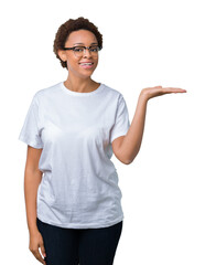 Beautiful young african american woman wearing glasses over isolated background smiling cheerful presenting and pointing with palm of hand looking at the camera.