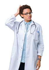 Young african american doctor woman wearing medical coat over isolated background confuse and wonder about question. Uncertain with doubt, thinking with hand on head. Pensive concept.