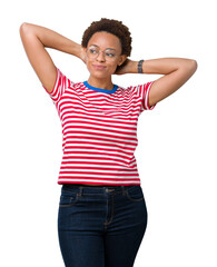 Obraz premium Beautiful young african american woman wearing glasses over isolated background Relaxing and stretching with arms and hands behind head and neck, smiling happy