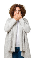 Beautiful middle ager senior woman wearing jacket and glasses over isolated background shocked covering mouth with hands for mistake. Secret concept.