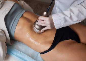 procedure removing cellulite on female abdomen, cavitation belly massage. Ultrasonic massage for...