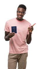 Young african american man holding german passport very happy pointing with hand and finger to the side