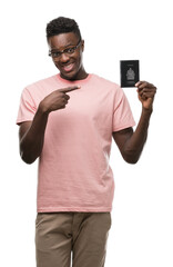 Young african american man holding canadian passport very happy pointing with hand and finger