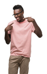 Young african american man wearing pink t-shirt smiling confident showing and pointing with fingers teeth and mouth. Health concept.