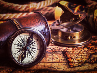 Travel geography navigation concept background - vintage retro effect filtered hipster style image of old vintage retro compass with sundial, spyglass and rope on ancient world map