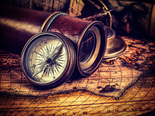 Travel geography navigation concept background - vintage retro effect filtered hipster style image of old vintage retro compass with sundial, spyglass and rope on ancient world map