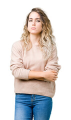 Beautiful young blonde woman wearing sweatershirt over isolated background skeptic and nervous, disapproving expression on face with crossed arms. Negative person.