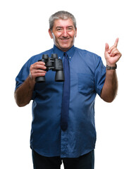 Handsome senior man looking through binoculars over isolated background very happy pointing with...