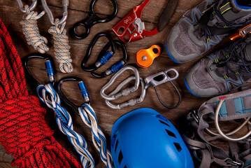 Climbing equipment for mountaineering and hiking helmet, hammer, carabiner, trekking shoes and other on wooden background, top view