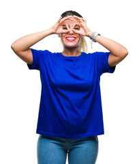 Fototapeta premium Young beautiful woman wearing casual blue t-shirt over isolated background doing ok gesture like binoculars sticking tongue out, eyes looking through fingers. Crazy expression.