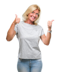 Fototapeta na wymiar Middle age blonde woman over isolated background success sign doing positive gesture with hand, thumbs up smiling and happy. Looking at the camera with cheerful expression, winner gesture.