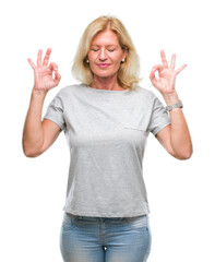 Fototapeta na wymiar Middle age blonde woman over isolated background relax and smiling with eyes closed doing meditation gesture with fingers. Yoga concept.