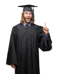 Young handsome graduated man with long hair over isolated background pointing finger up with successful idea. Exited and happy. Number one.