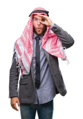 Fototapeta premium Young handsome arabian man with long hair wearing keffiyeh over isolated background doing ok gesture shocked with surprised face, eye looking through fingers. Unbelieving expression.
