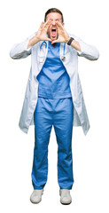 Handsome doctor man wearing medical uniform over isolated background Shouting angry out loud with hands over mouth