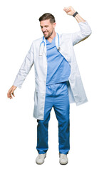 Handsome doctor man wearing medical uniform over isolated background Dancing happy and cheerful, smiling moving casual and confident listening to music