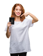Young beautiful woman holding passport of canada over isolated background very happy pointing with hand and finger
