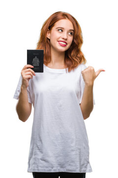 Young beautiful woman holding passport of canada over isolated background pointing and showing with thumb up to the side with happy face smiling