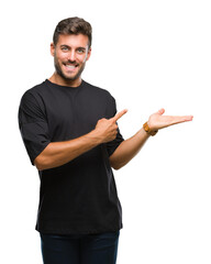 Young handsome man over isolated background amazed and smiling to the camera while presenting with hand and pointing with finger.