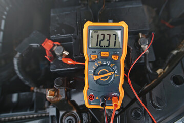 Multimeter checking car battery voltage level. Check car battery using voltmeter. Man check up...