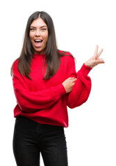 Young beautiful hispanic wearing red sweater smiling with happy face winking at the camera doing victory sign. Number two.