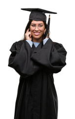 Young hispanic woman wearing graduated cap and uniform covering ears with fingers with annoyed expression for the noise of loud music. Deaf concept.