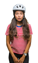 Young arab cyclist woman wearing safety helmet over isolated background afraid and shocked with surprise expression, fear and excited face.