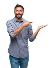 Adult hispanic man over isolated background amazed and smiling to the camera while presenting with hand and pointing with finger.