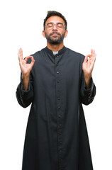 Fototapeta premium Adult hispanic catholic priest man over isolated background relax and smiling with eyes closed doing meditation gesture with fingers. Yoga concept.