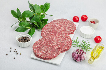 Raw burger patties. Fresh meat cutlets, spices, vegetables, herbs. Homemade American classic