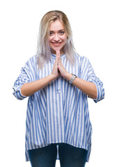 Young blonde woman over isolated background praying with hands together asking for forgiveness smiling confident.