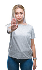 Young blonde woman over isolated background doing stop sing with palm of the hand. Warning...