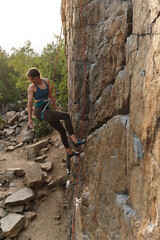 Naklejka na ściany i meble young professional sportswoman of athletic body - climber climbing a rock, on a mountain 