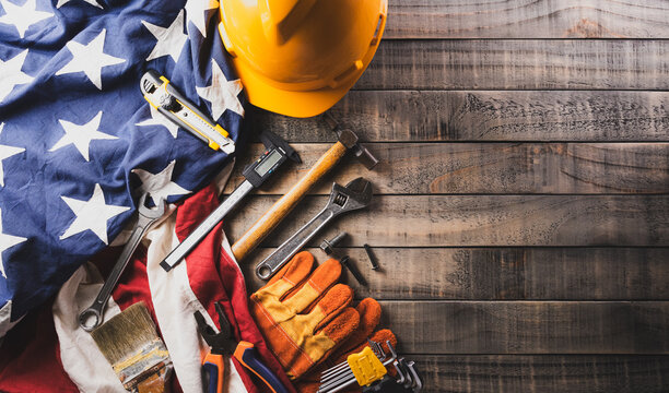 Happy Labor day concept. American flag with different construction tools on dark wooden background.