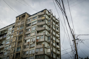 The grey Soviet style old building and the street intertangled wires in the city of Mahachkala,...