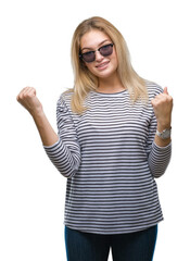 Obraz na płótnie Canvas Young caucasian woman wearing sunglasses over isolated background celebrating surprised and amazed for success with arms raised and open eyes. Winner concept.